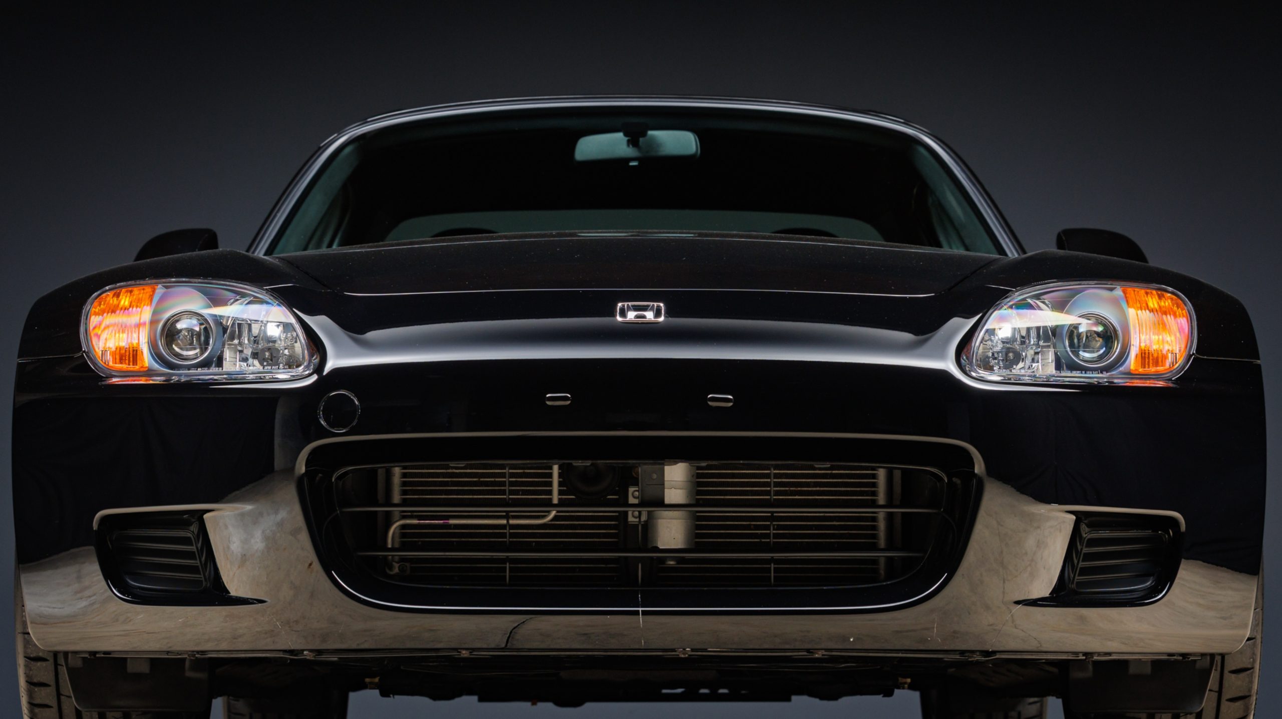 Front view of a black Honda S2000 AP1 showing the iconic headlights and grille design