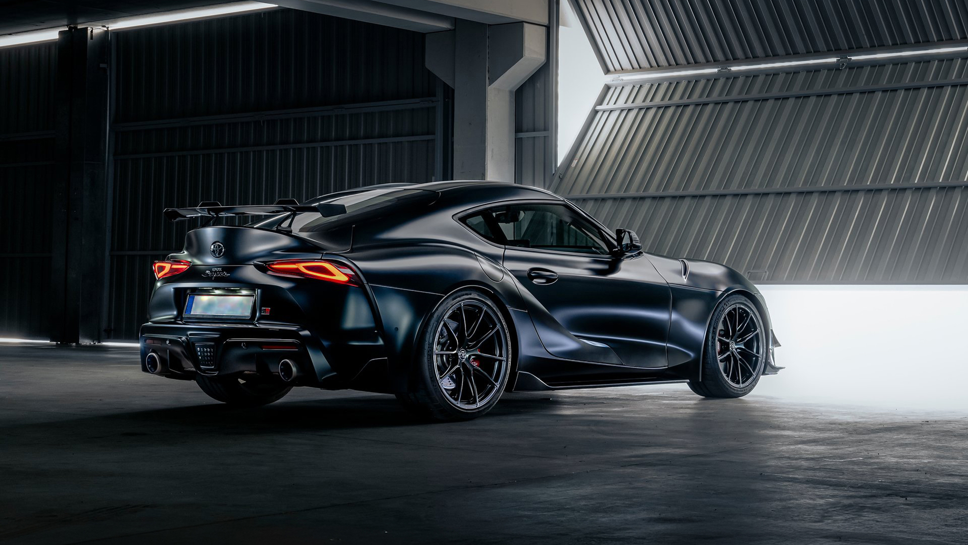 Black Toyota GR Supra rear three quarter view inside an industrial studio setting