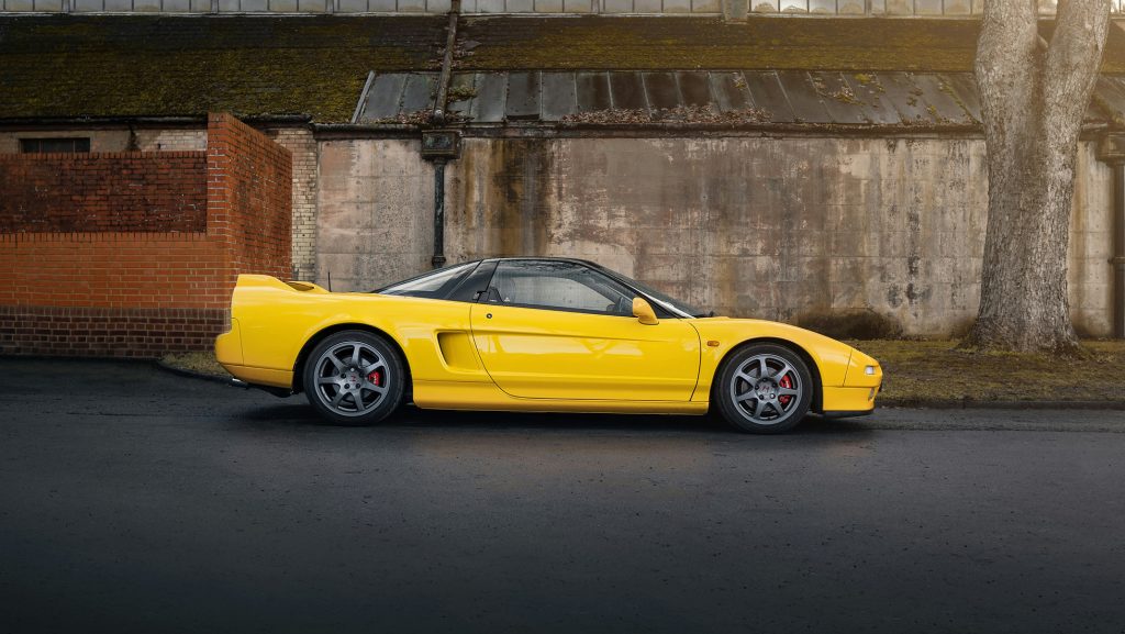 Yellow Honda NSX parked roadside in side profile showing classic mid engine Japanese sports car styling
