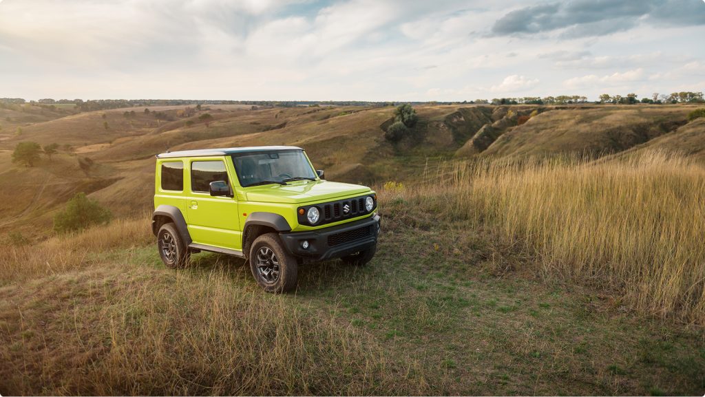 Suzuki Jimny Sierra parked in open countryside showcasing compact Japanese 4WD styling and off road capability