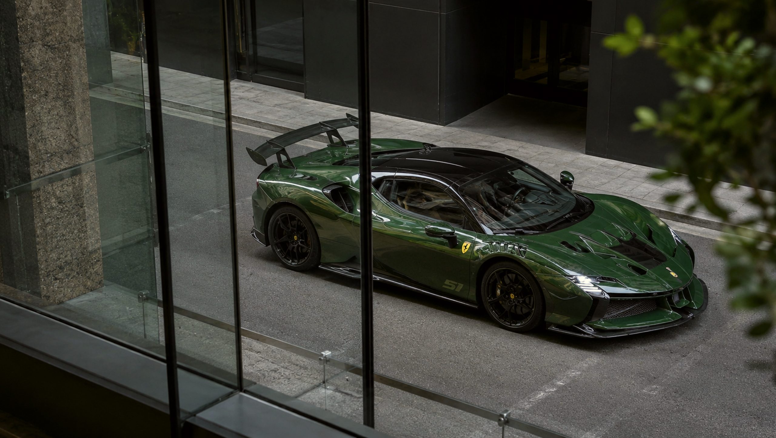 Green Ferrari SF90 XX Stradale parked in an urban setting viewed through glass windows